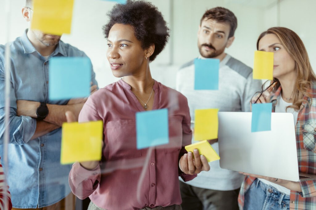 Group of small business entrepreneurs surrounded by sticky notes, looking busy